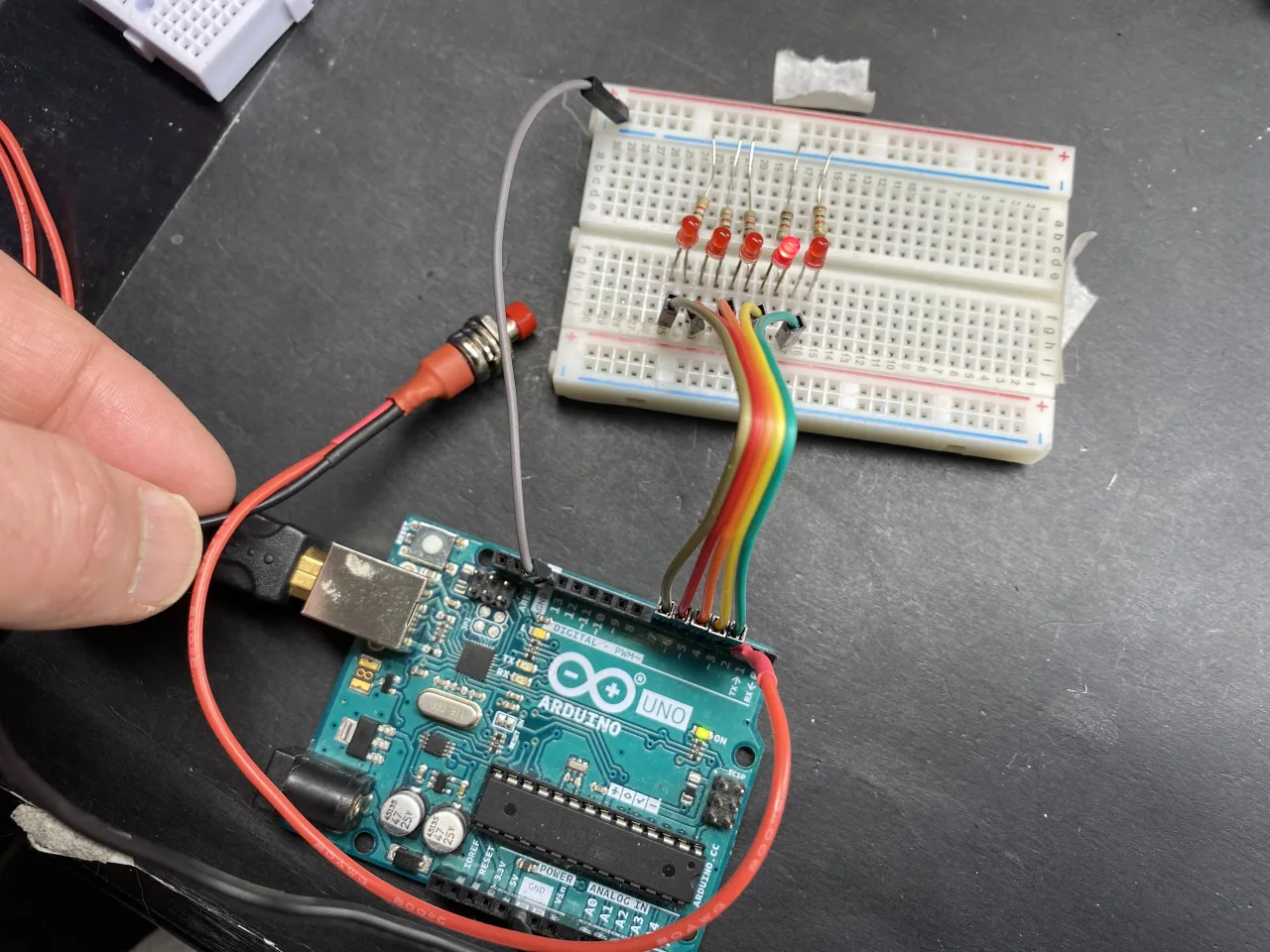 5 leds on breadboard with push button shown connected to Arduino UNO